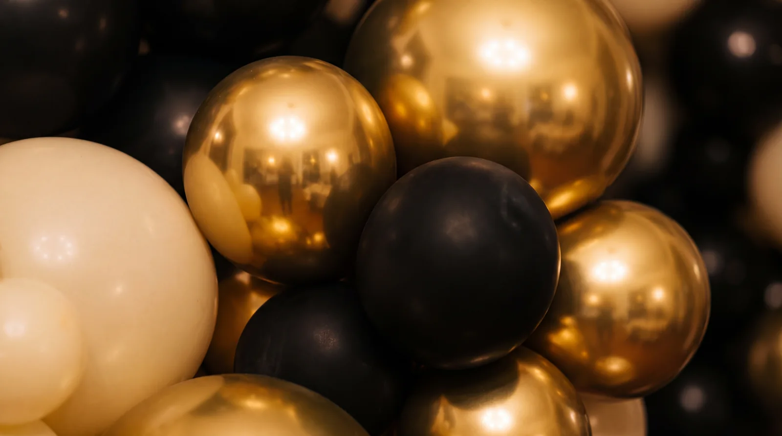 Close up of chrome gold, matte black and ivory balloons packed together