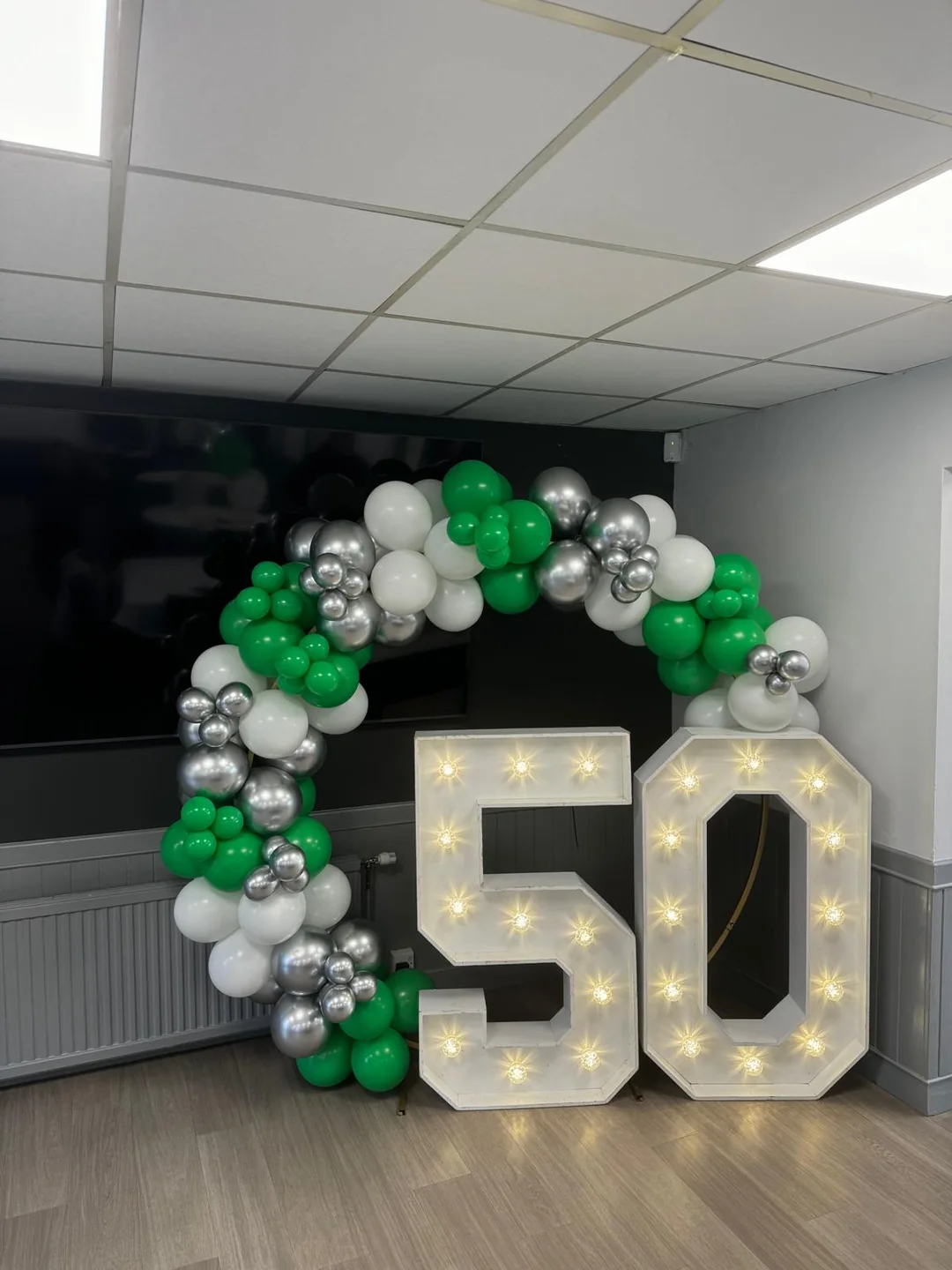 A light up 50 with a green, silver and white balloon garland