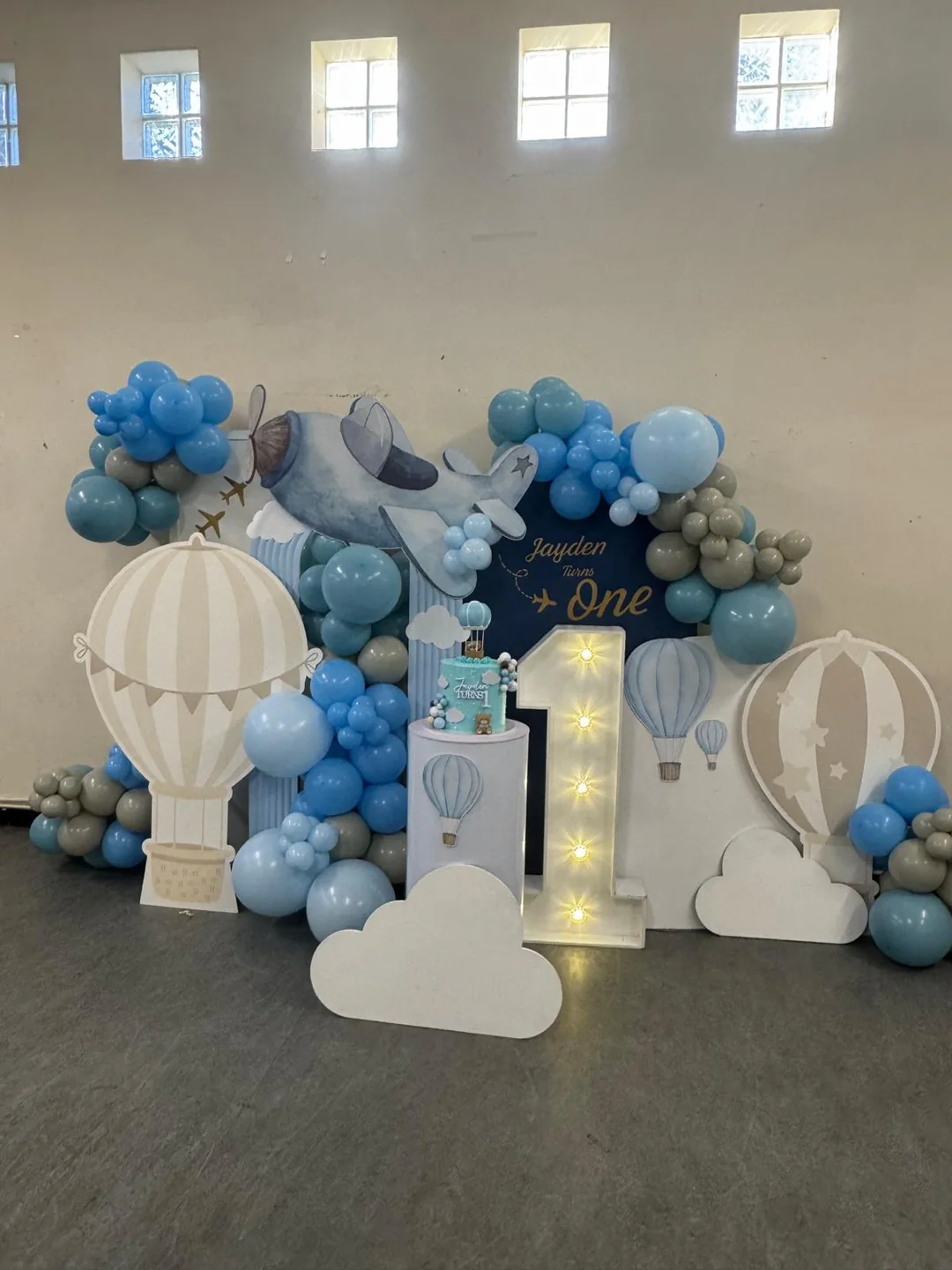 An aeroplane and hot air balloon first birthday with clouds and a light up number one