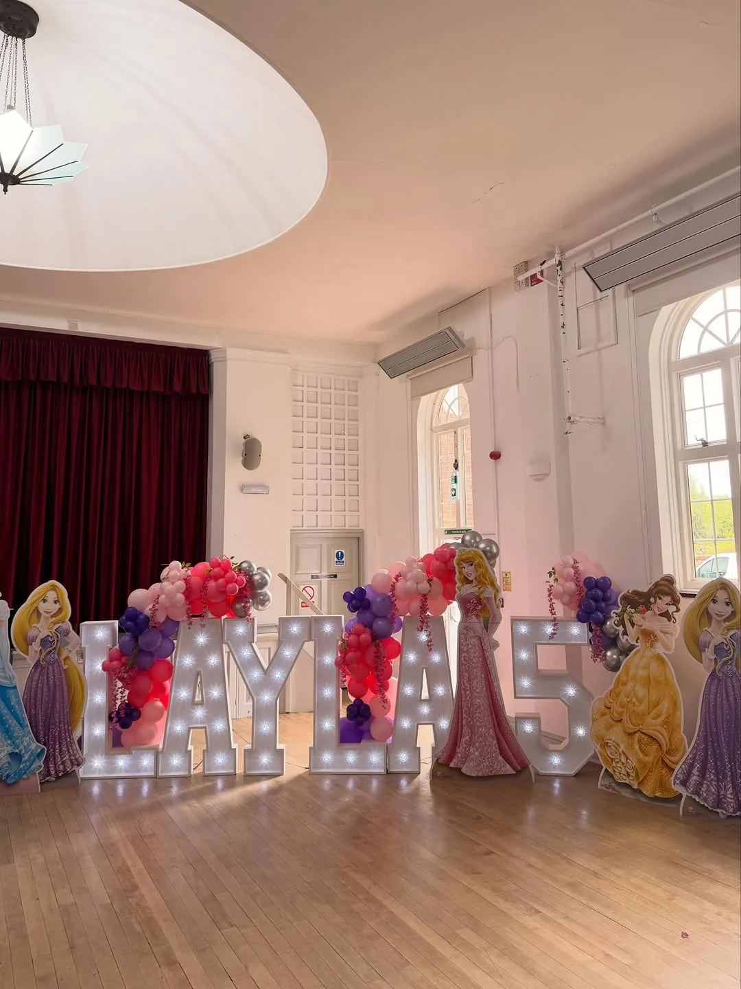 A ballroom with light up letters and princess cutouts