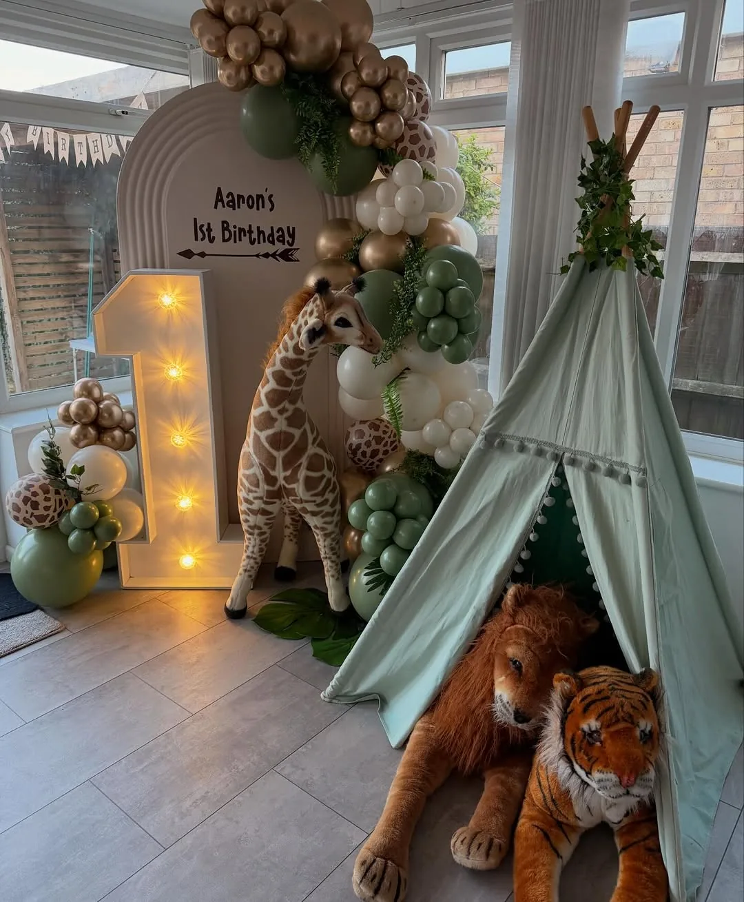 A light up number one beside a giraffe and a safari garland