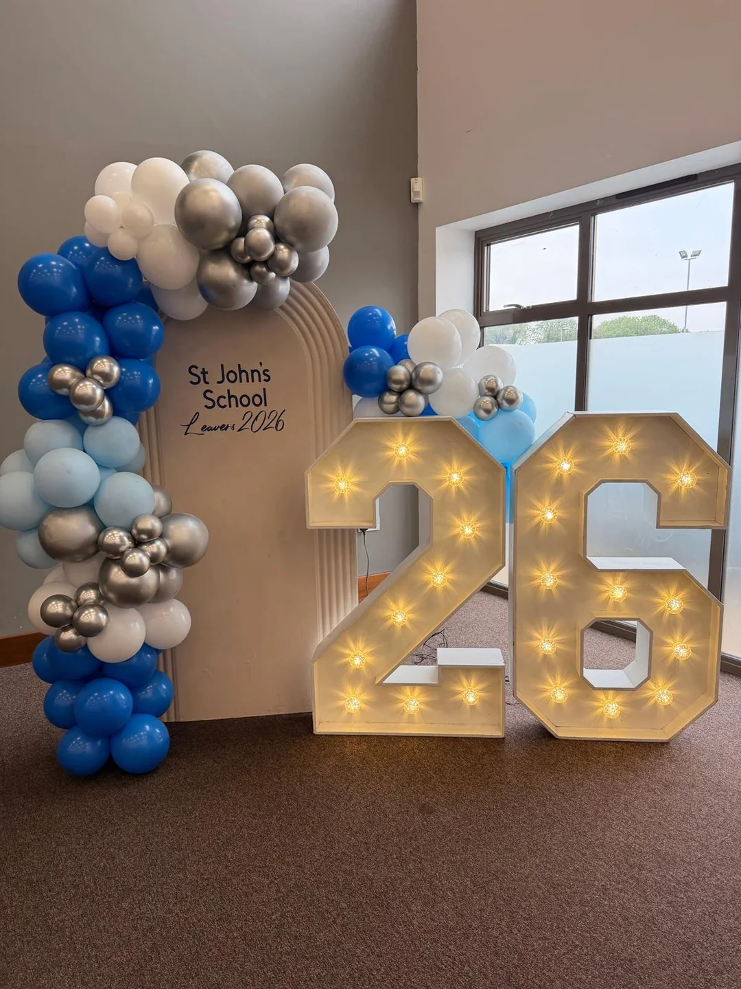 A school leavers display with a blue, white and chrome balloon arch beside a light up 26