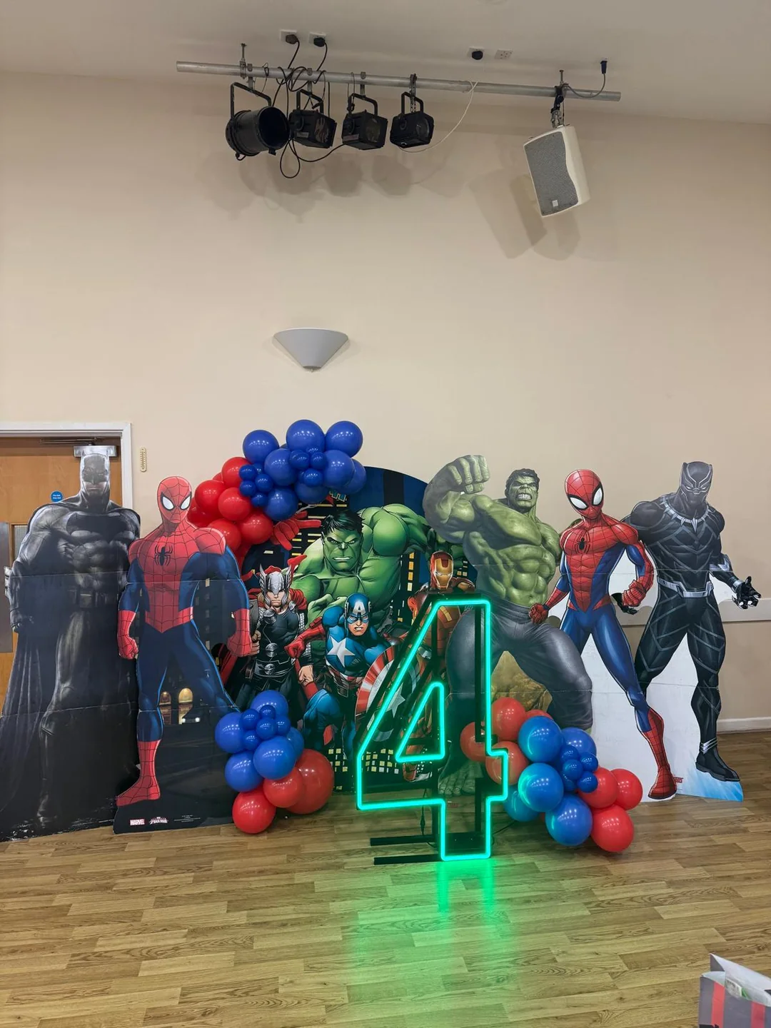 A superhero themed fourth birthday with character cutouts and a green neon number four