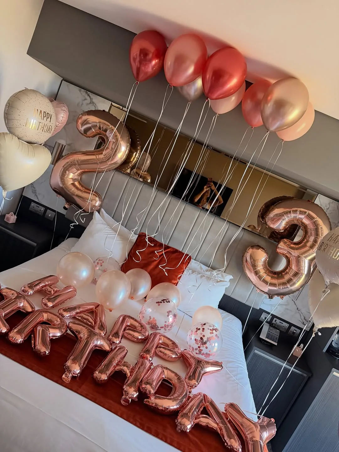 Rose gold number and letter balloons arranged across a bedroom