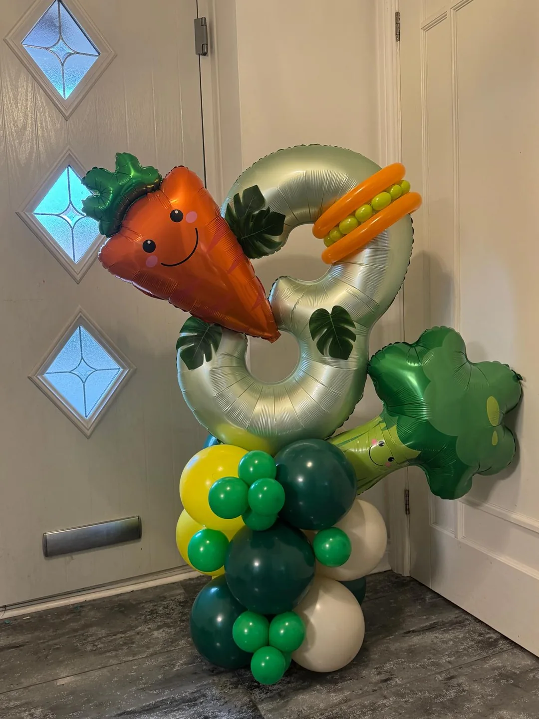 A number three balloon stack built with carrot, pea and broccoli foil balloons