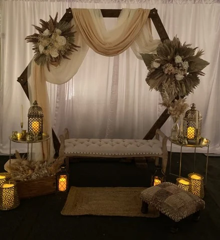 Draped ceremony arch with dried florals and lanterns